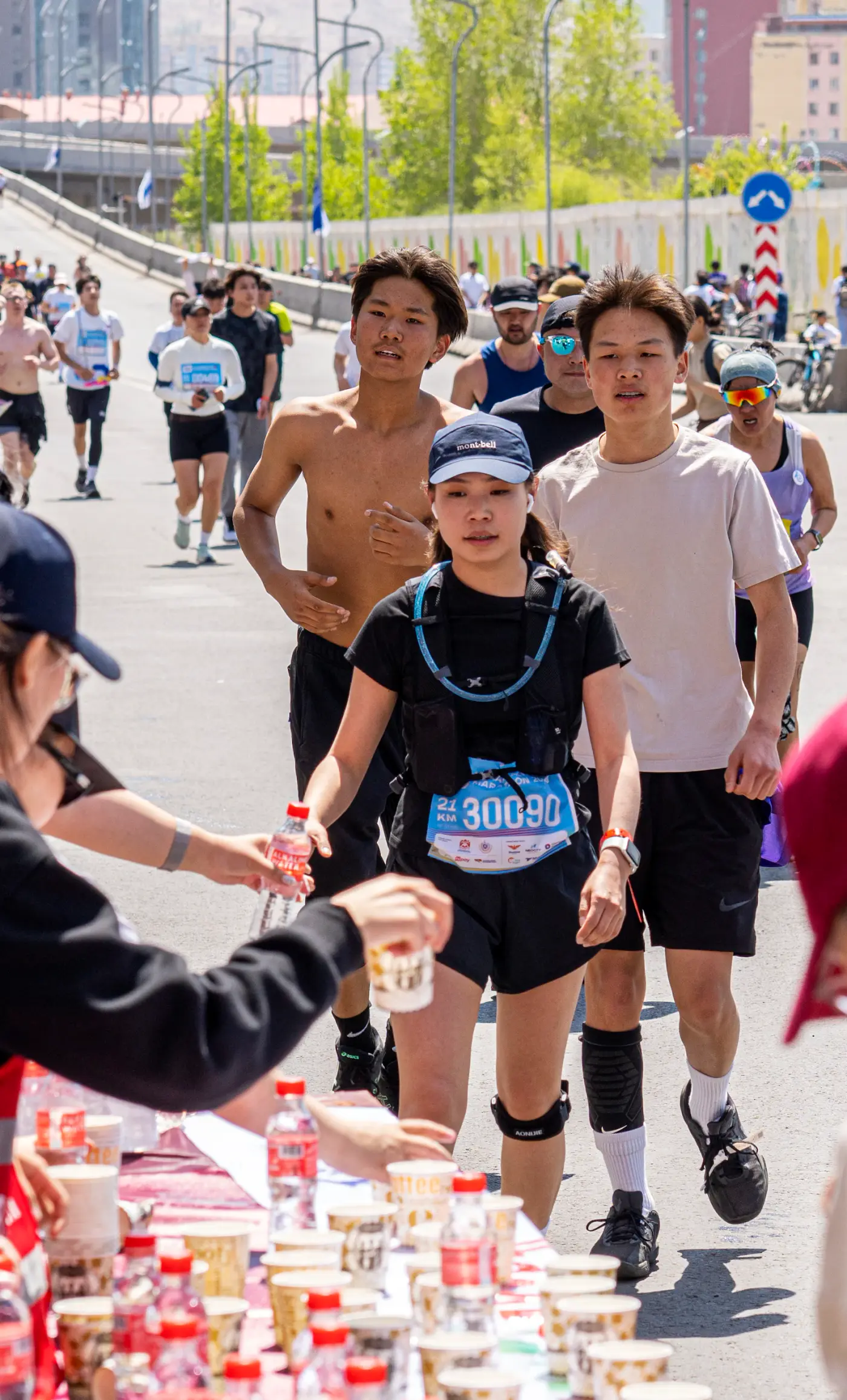 給水ポイントでボランティアから水を受け取るランナー
